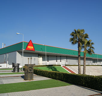 Strahlend blauer Himmel und zwei Palmen schmücken das Produktionsgebäude von Delta Cafés