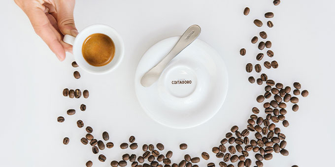 Ein Espresso neben einer Untertasse und Kaffeebohnen