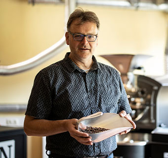 Ein Mann präsentiert frisch geröstete Kaffeebohnen