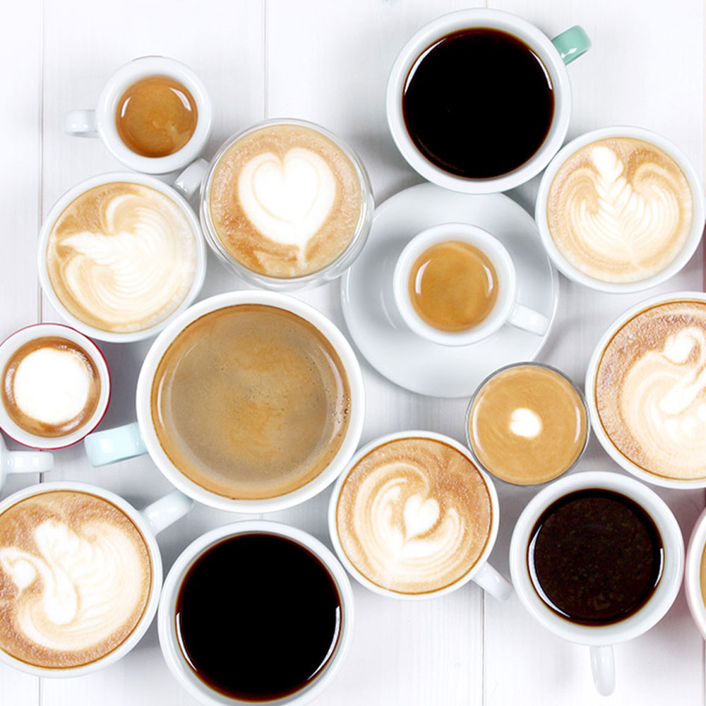 Cappuccini, Espressi, schwarzer Filterkaffee und viele weitere Kaffeespezialitäten auf der weißen Tischplatte
