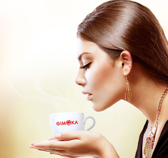 Eine Frau hält eine Tasse dampfenden Kaffee in der Hand