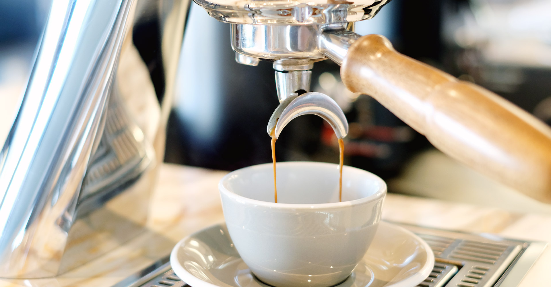 Kaffee läuft aus einem Siebträger in eine beige Tasse
