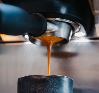 Kaffee läuft aus einem Siebträger in eine Tasse