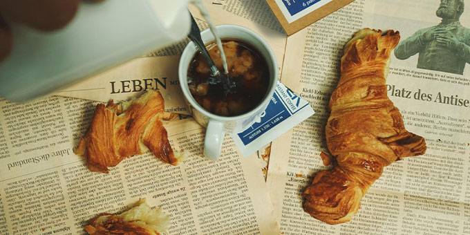 Tasse Kaffee und Croissants liegen auf Zeitung